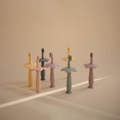 Mushie Escova de dentes de treinamento em silicone, para bebês e crianças pequenas, com base de sucção para fácil armazenamento e treinamento, material: silicone de qualidade alimentar, design de flor (narciso claro).