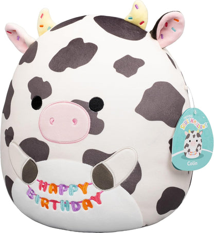 Squishmallows Original de 12 Polegadas – Colin, a Vaca Malhada, Segurando Placa de Aniversário – Pelúcia Oficial Jazwares (Tamanho Médio)